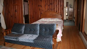 Ein Zimmer mit Holzwänden, einem Bett, einer Couch und einem Sessel.