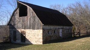 Ein rustikaler Schuppen mit geneigtem Dach, Stein Fundament und Holzwänden.