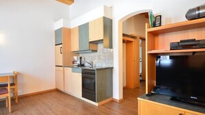 Una cucina compatta con mobili in legno, forno integrato e macchina da caffè.