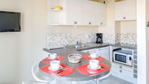 Una cucina moderna con mobili bianchi, zoccolo di piastrelle, microonde e macchina per il caffè.