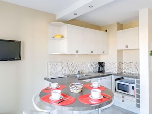 Eine moderne Küche mit weißen Schränken, einer gefliesten Spritzschutzwand, einer Mikrowelle und einer Kaffeemaschine.