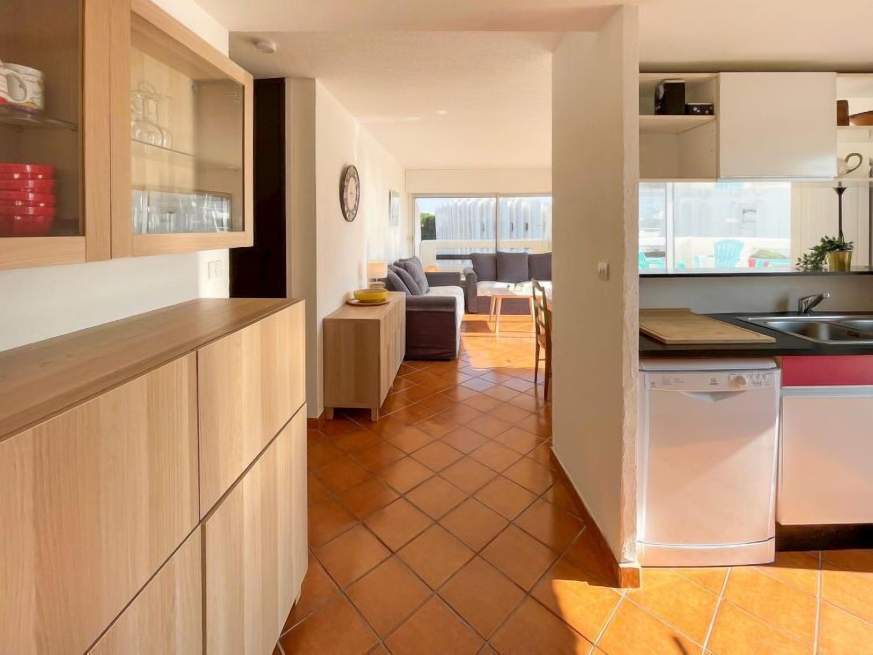 Una cocina moderna con lavavajillas, un comedor con mesa y sillas, y una sala de estar con sofá.
