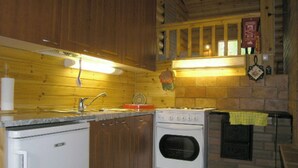 A compact kitchen with wooden cabinets, a built-in oven, and a sink. - Vacation home Rihka by Interhome (Hämeenlinna)