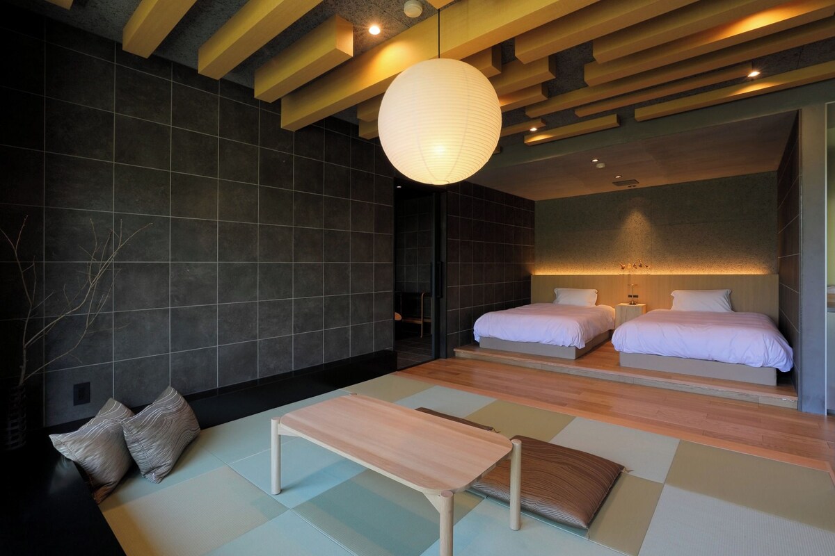 Un dormitorio moderno con dos camas, un banco de madera y una lámpara colgante grande.