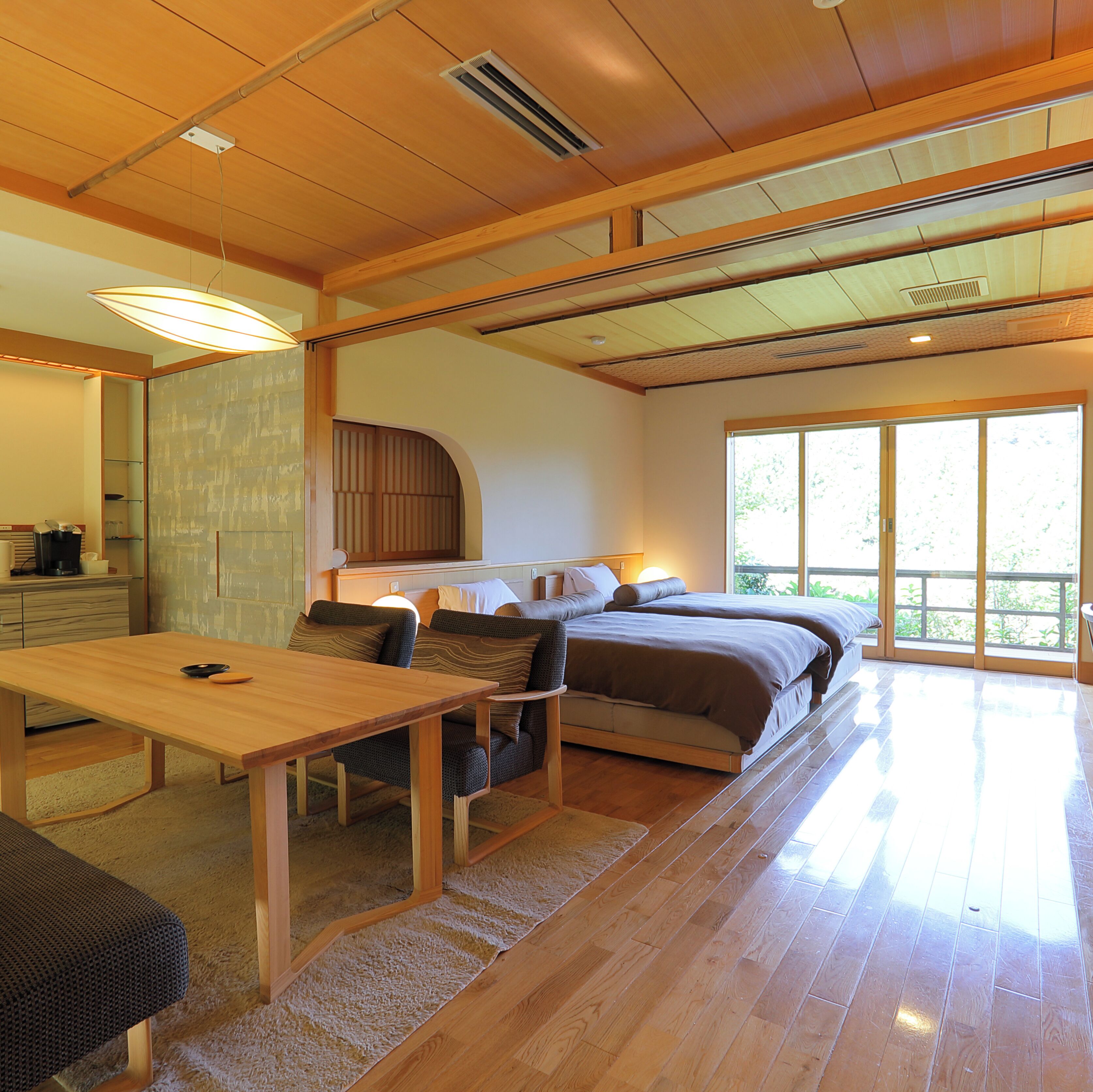 A modern bedroom with a large bed, a wooden table, and a sofa.