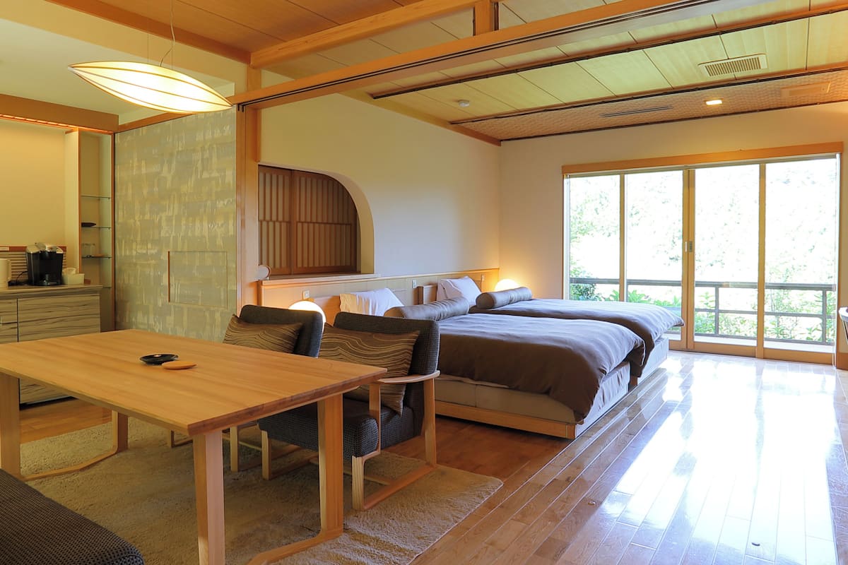 A modern bedroom with a large bed, a wooden table, and a sofa.