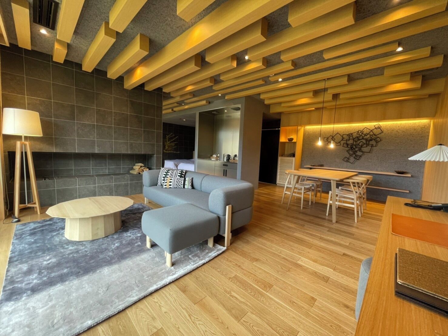 A modern living room with a sofa, ottoman, round coffee table, and a dining area with a table and chairs.