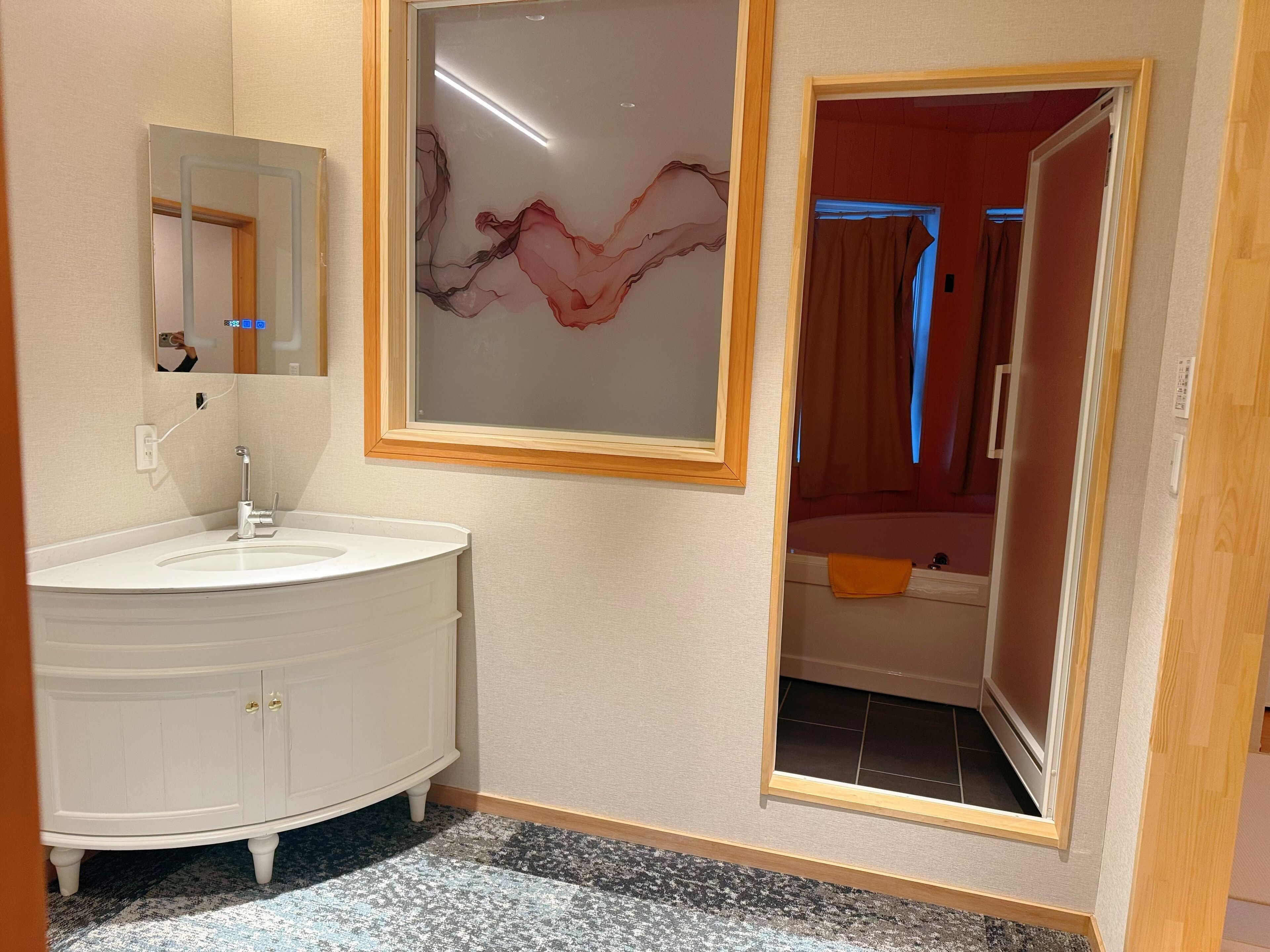 A bathroom with a white vanity, a mirror, and a framed abstract artwork on the wall.