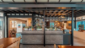A bar area with a marble countertop, wooden chairs, and a variety of bottles.