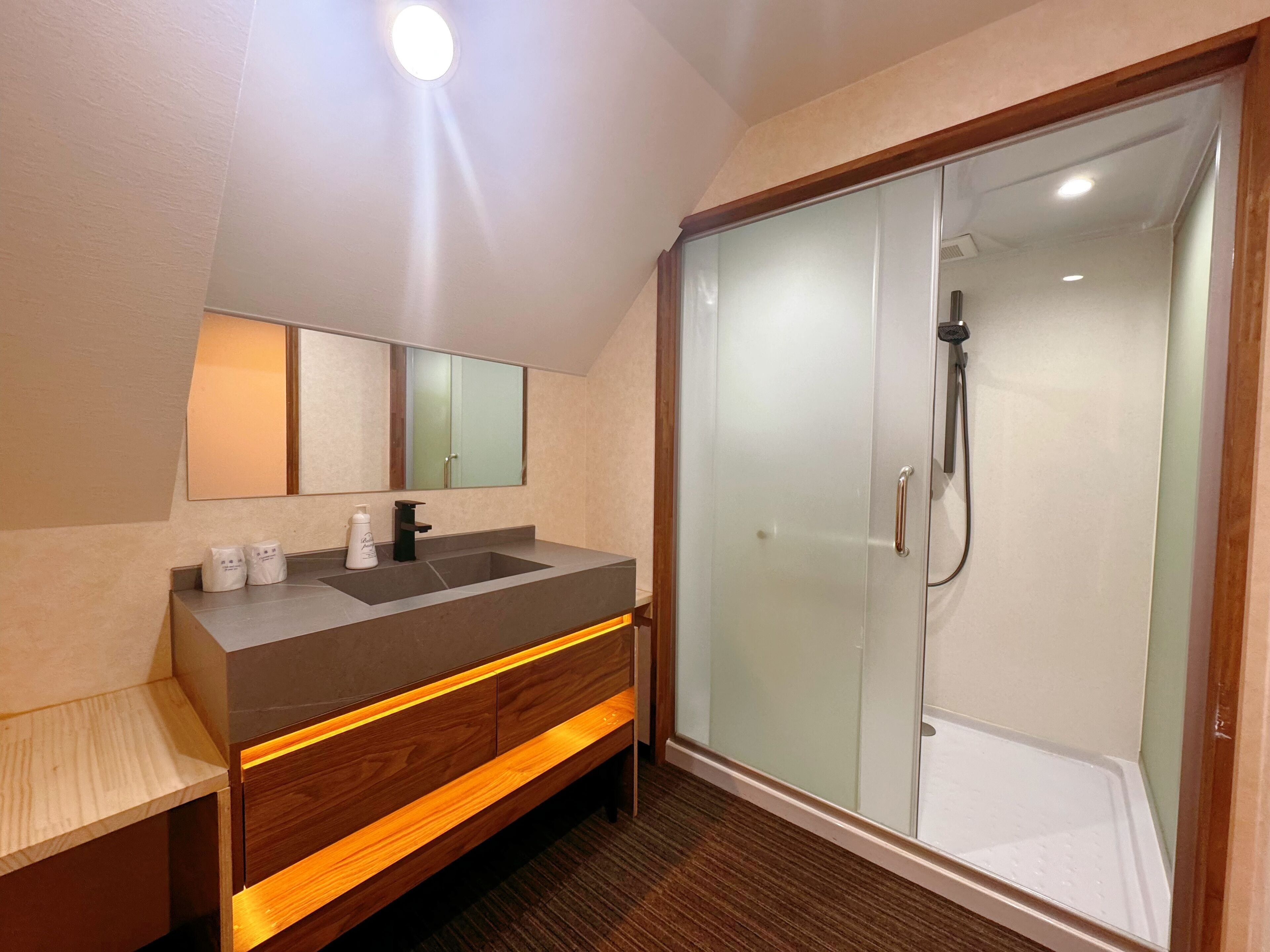A modern bathroom with a large mirror, a sink, and a glass-enclosed shower.
