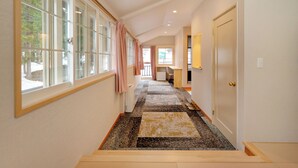 A hallway with large windows, a carpeted floor, and a door on the right.