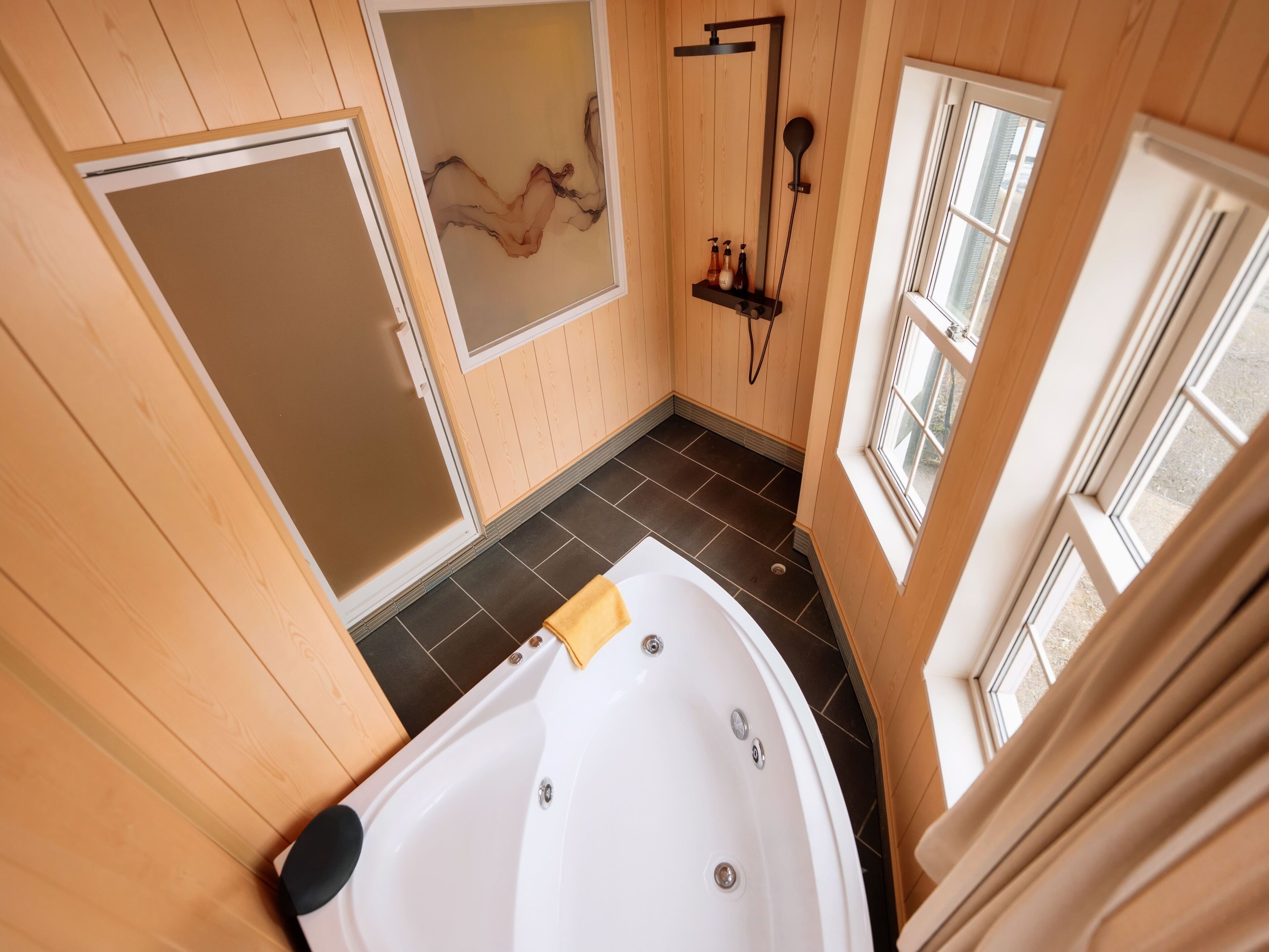 Un baño con bañera, ducha y ventana.