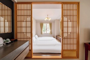 A traditional Japanese-style room with a bed, wooden sliding doors, a dresser, and a mirror.