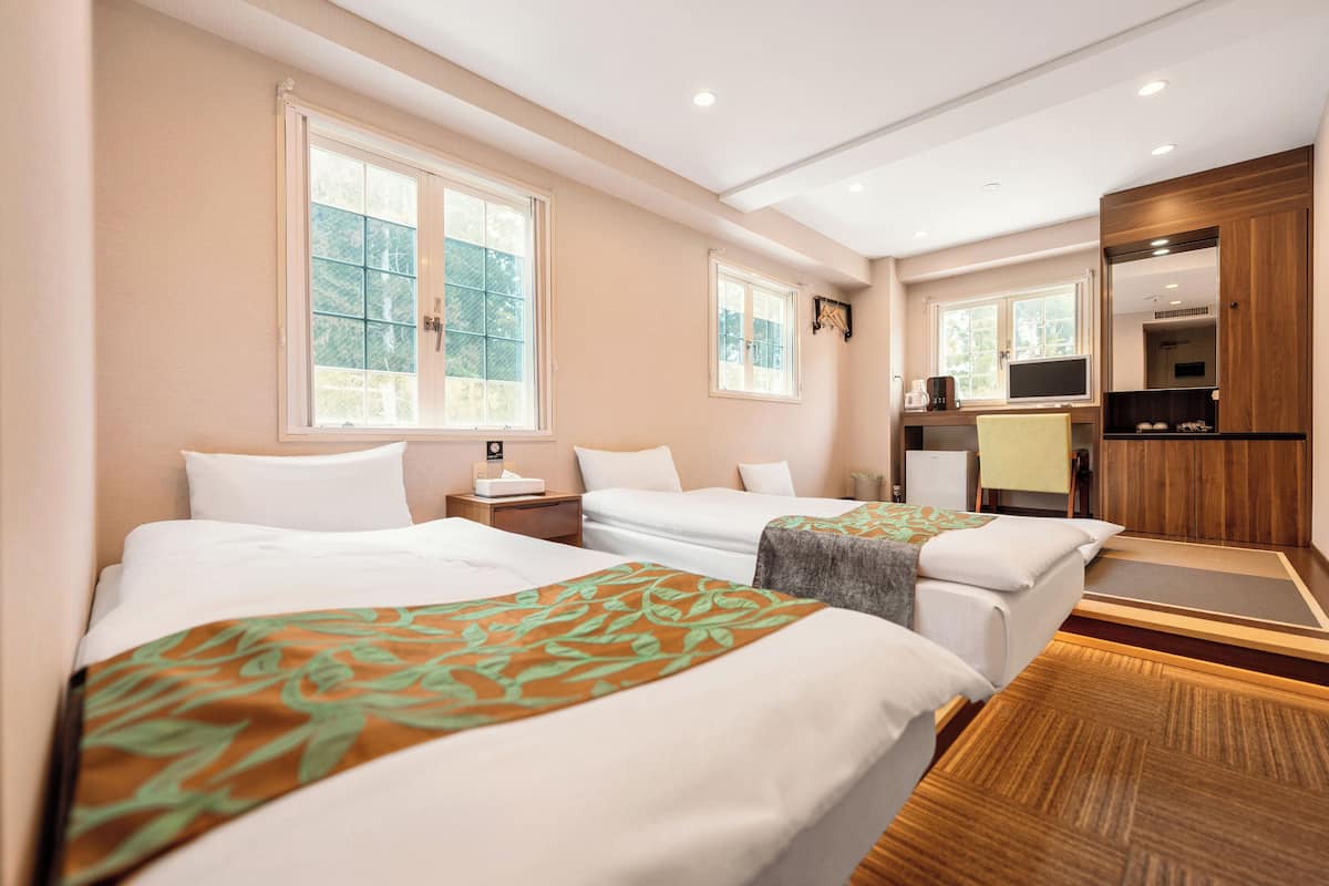 Une chambre d’hôtel avec deux lits, un bureau et une télévision.