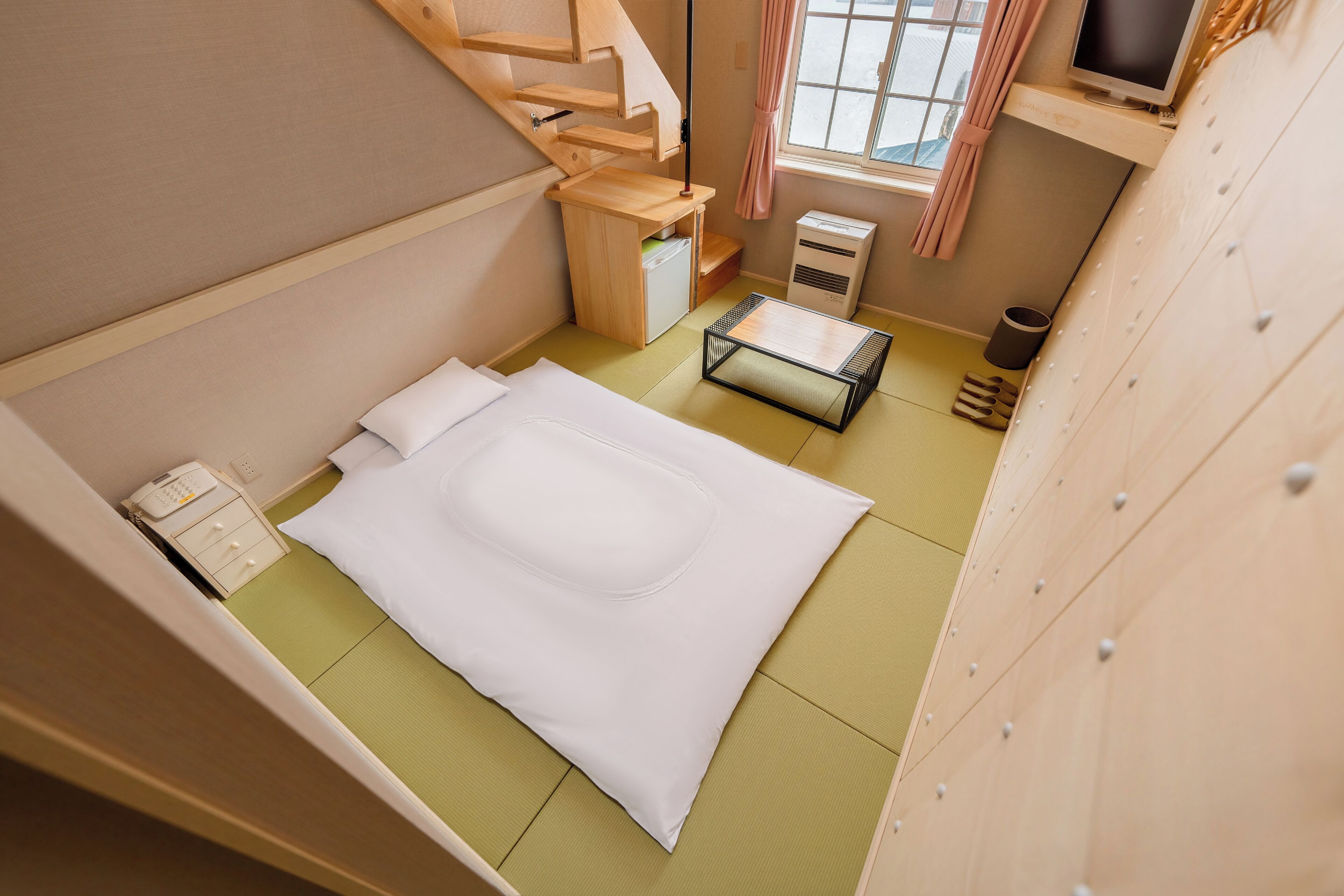 Habitación compacta con cama, un escritorio pequeño, un calentador y una ventana con cortinas.