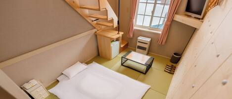 Habitación compacta con cama, un escritorio pequeño, un calentador y una ventana con cortinas.