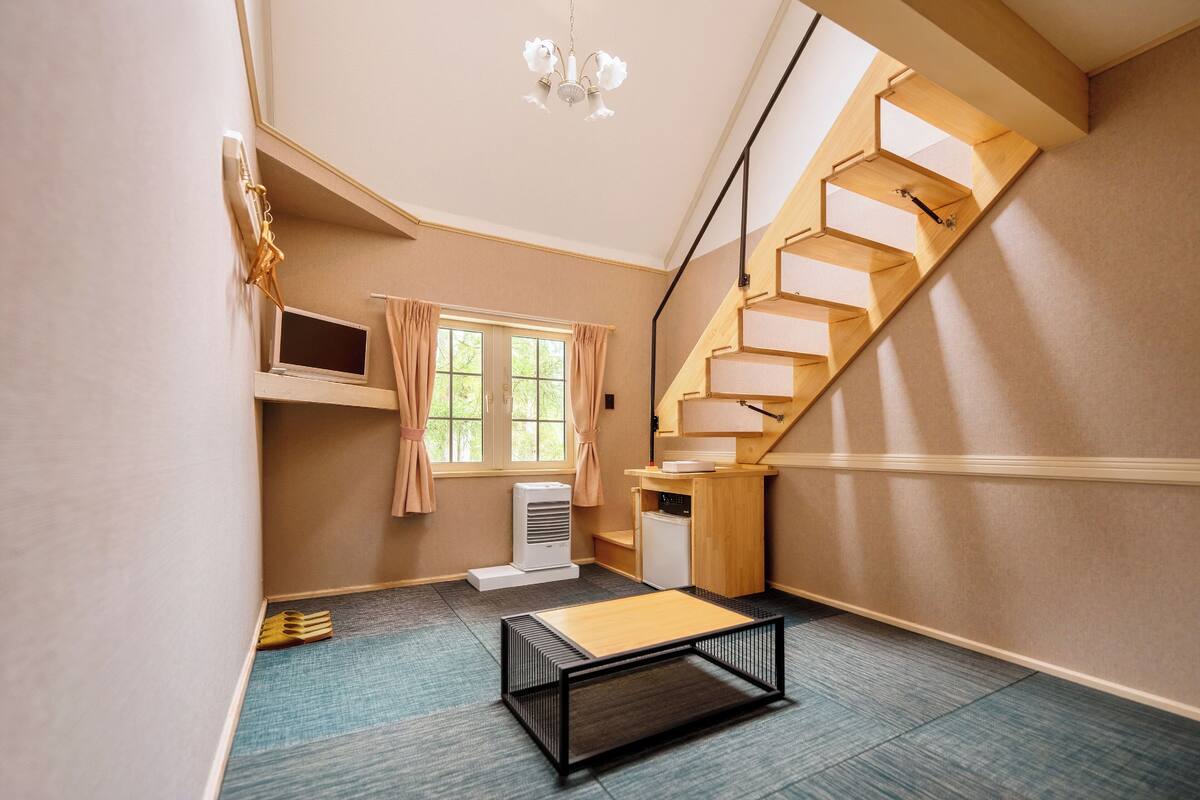 Une pièce moderne avec un escalier en bois, une petite table et une fenêtre avec des rideaux.