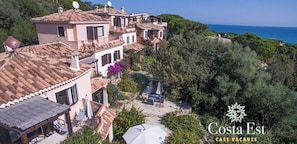 A coastal property with terracotta tiled roofs, a patio with outdoor furniture, and a view of the sea.