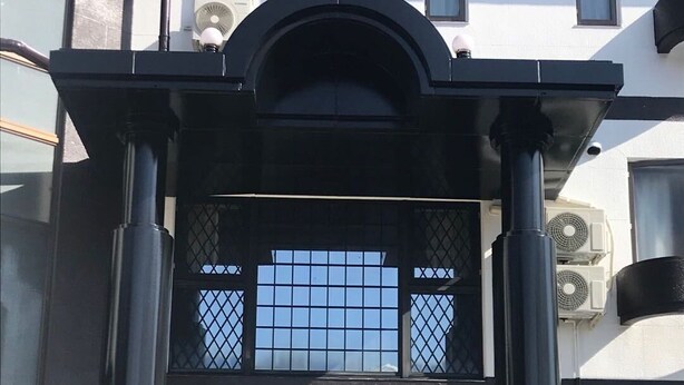 A building with a black-framed entrance, large windows, and air conditioning units. - Asia Hotel Kawaguchiko (Fujikawaguchiko)
