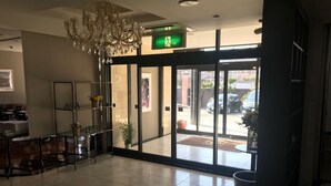 A hotel lobby with a chandelier, a reception desk, a plant, and a view of the street outside. - Asia Hotel Kawaguchiko (Fujikawaguchiko)