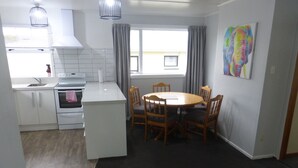 A compact kitchen with white cabinets, a stove, and a dining area with a wooden table and chairs.