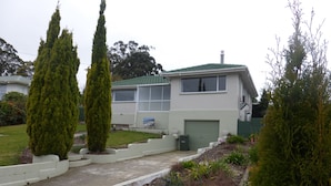 A two-story house with a green roof, a garage, and a front yard with a pathway leading to the entrance.