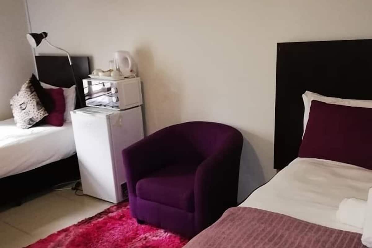 Une chambre d’hôtel avec un lit, une table de chevet, une chaise et un tapis rouge.