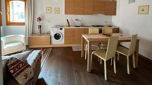 A cozy kitchen with wooden beams, a dining area, and a washing machine. - Al Piccolo Clarin (Mestre)
