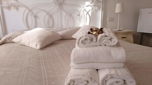 A neatly made bed with rolled white towels and a decorative headboard. - Al Piccolo Clarin (Mestre)