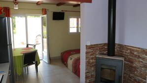 A kitchen with a stove, a dining table with chairs, and a view of the outside. - Small studio / Furnished rental (Neuwiller-lès-Saverne)