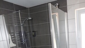 A glass-enclosed shower with a tiled floor, a white sink, and a washing machine. - Small studio / Furnished rental (Neuwiller-lès-Saverne)