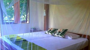 A bed with a canopy, a pillow, and a green bedspread. - Berakit Bay Resort (Bintan)