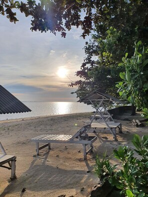 A beach with lounge chairs and a small shelter. - Berakit Bay Resort (Bintan)