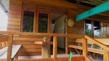 Una cabaña de madera con balcón, una mesita y una planta en maceta.