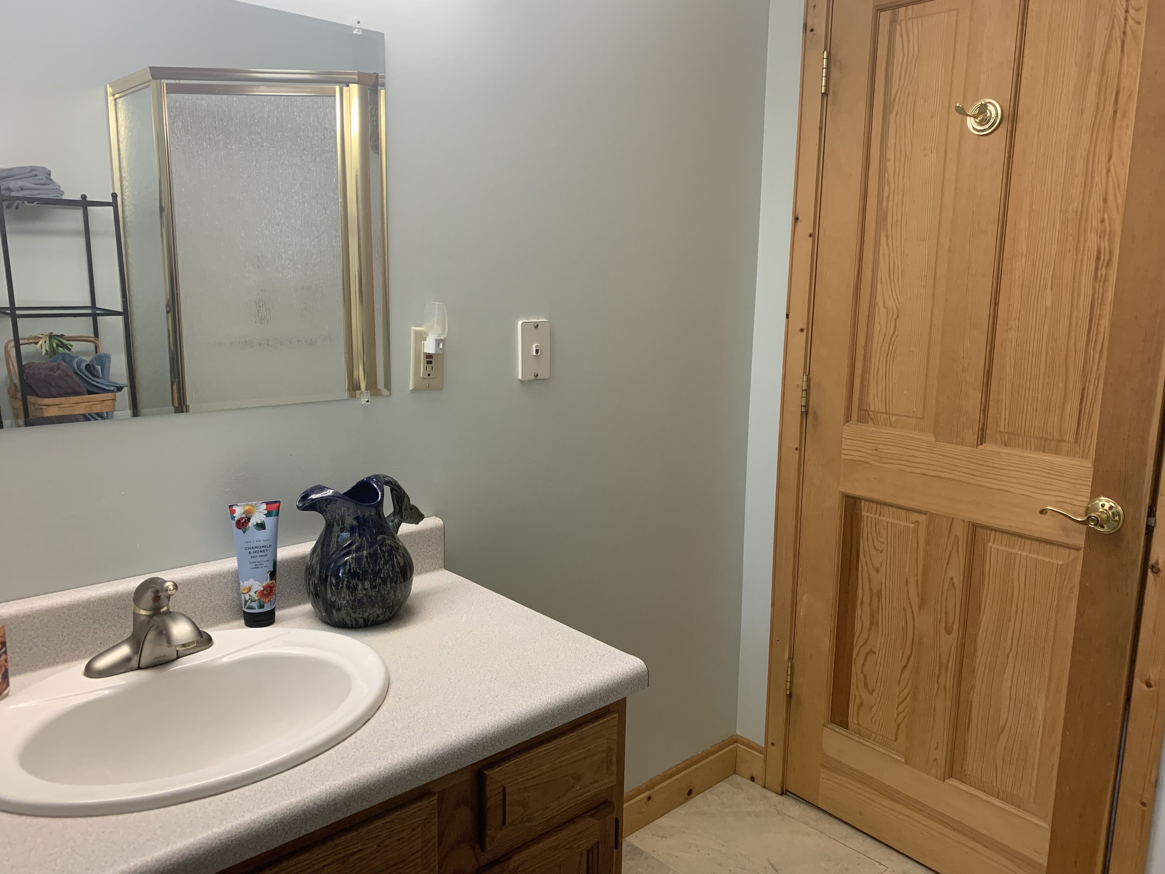 A bathroom with a white sink, a mirror, a wooden door, and a small towel rack.
