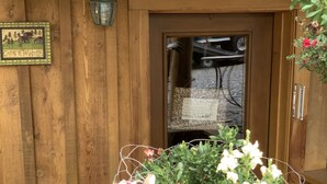 A wooden deer head planter with flowers, a wooden door, and a sign on the wall. - Sawinglogzz Log Cabin (Copper Center)