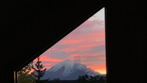 A mountain view through a window with a visible tree line and a clear sky. - Sawinglogzz Log Cabin (Copper Center)