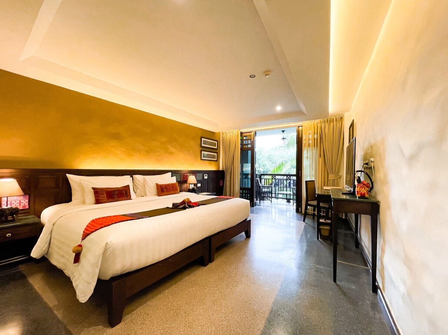 Una habitación de hotel con una cama grande, un escritorio y un balcón con cortinas.