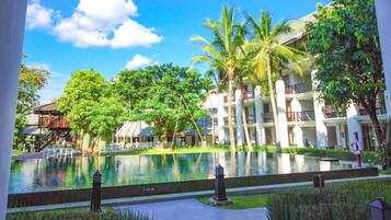 A resort with a pool, palm trees, and a building with balconies.