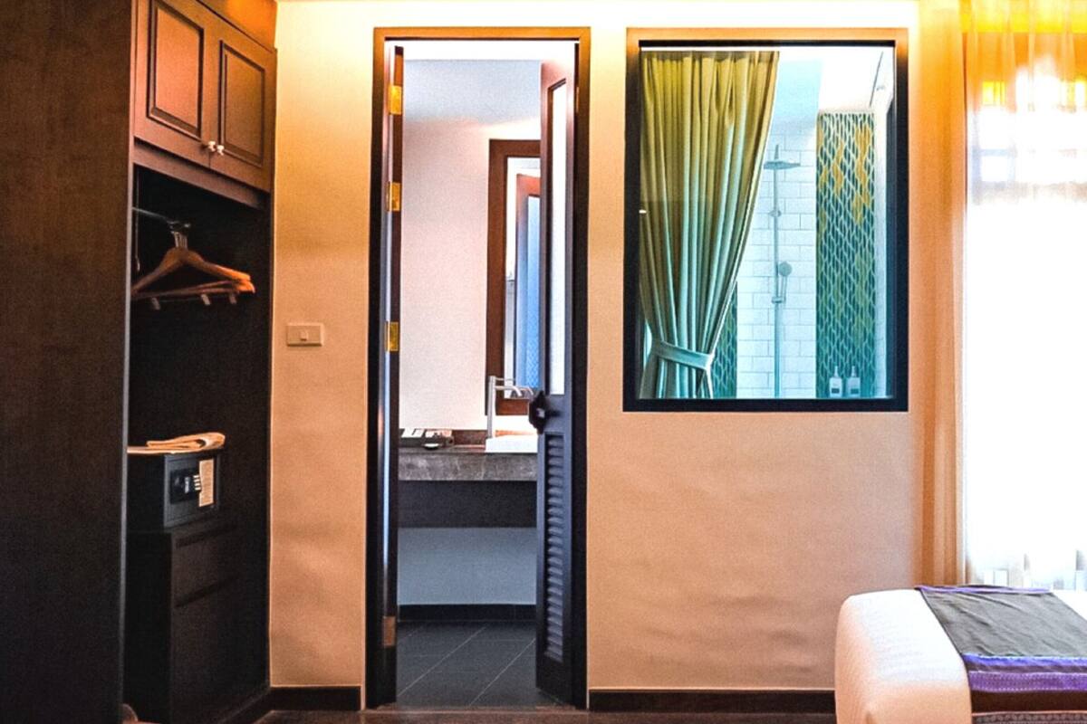 Une chambre d’hôtel avec un lit, une armoire, une salle de bain et une fenêtre avec des rideaux.