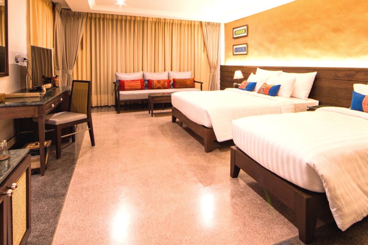 Une chambre d’hôtel avec deux lits, un bureau, une chaise et un téléviseur.