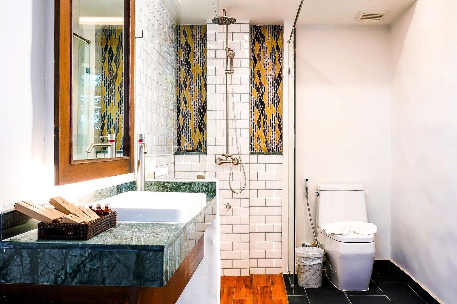 Une salle de bain moderne avec un lavabo en marbre, une douche équipée d’un pommeau de douche amovible et des toilettes.