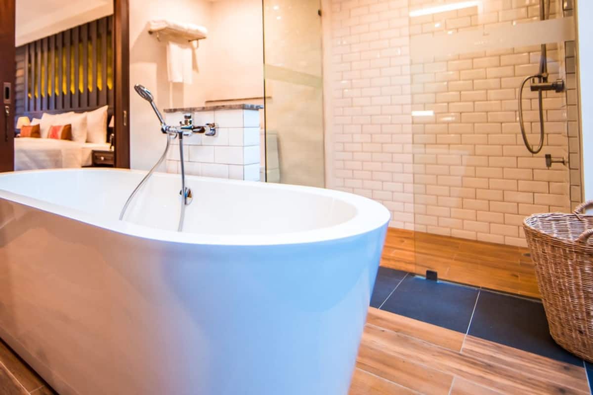 Une salle de bain moderne avec une baignoire sur pieds, une cabine de douche en verre et un panier en osier.