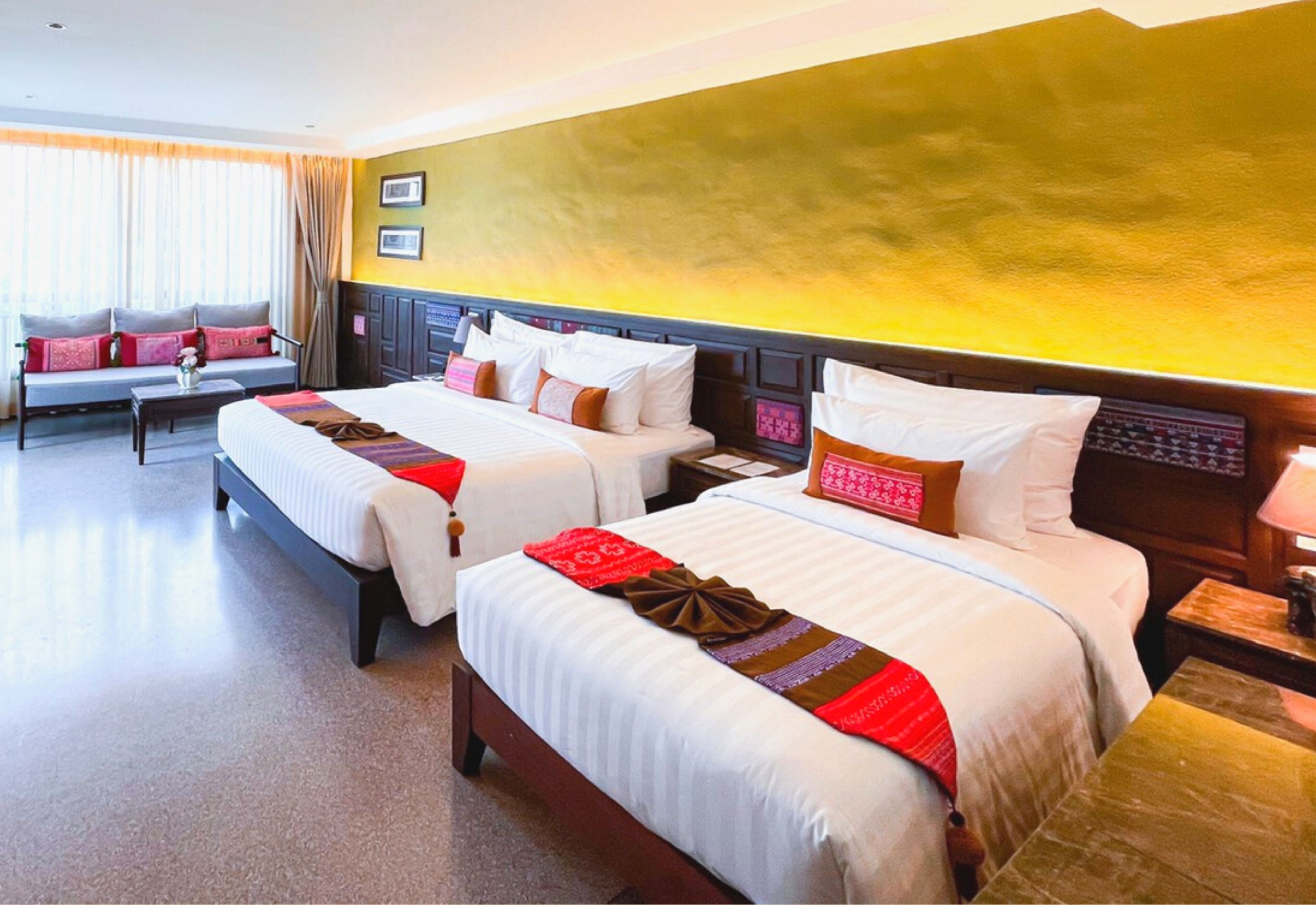 A hotel room with two beds, a sofa, and a small table.