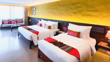 A hotel room with two beds, a sofa, and a small table.