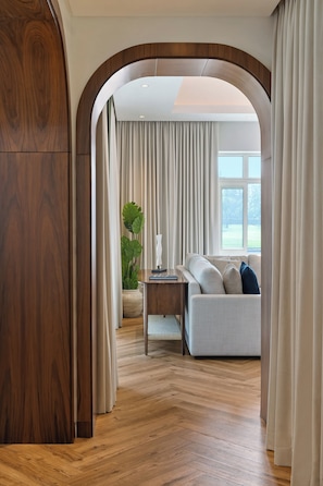Een moderne woonkamer met een houten vloer, een bank, een salontafel en een potplant.