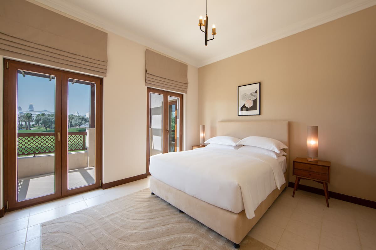 Una camera da letto con un letto grande, un comodino, una lampada e vista su una zona esterna tramite una porta scorrevole.