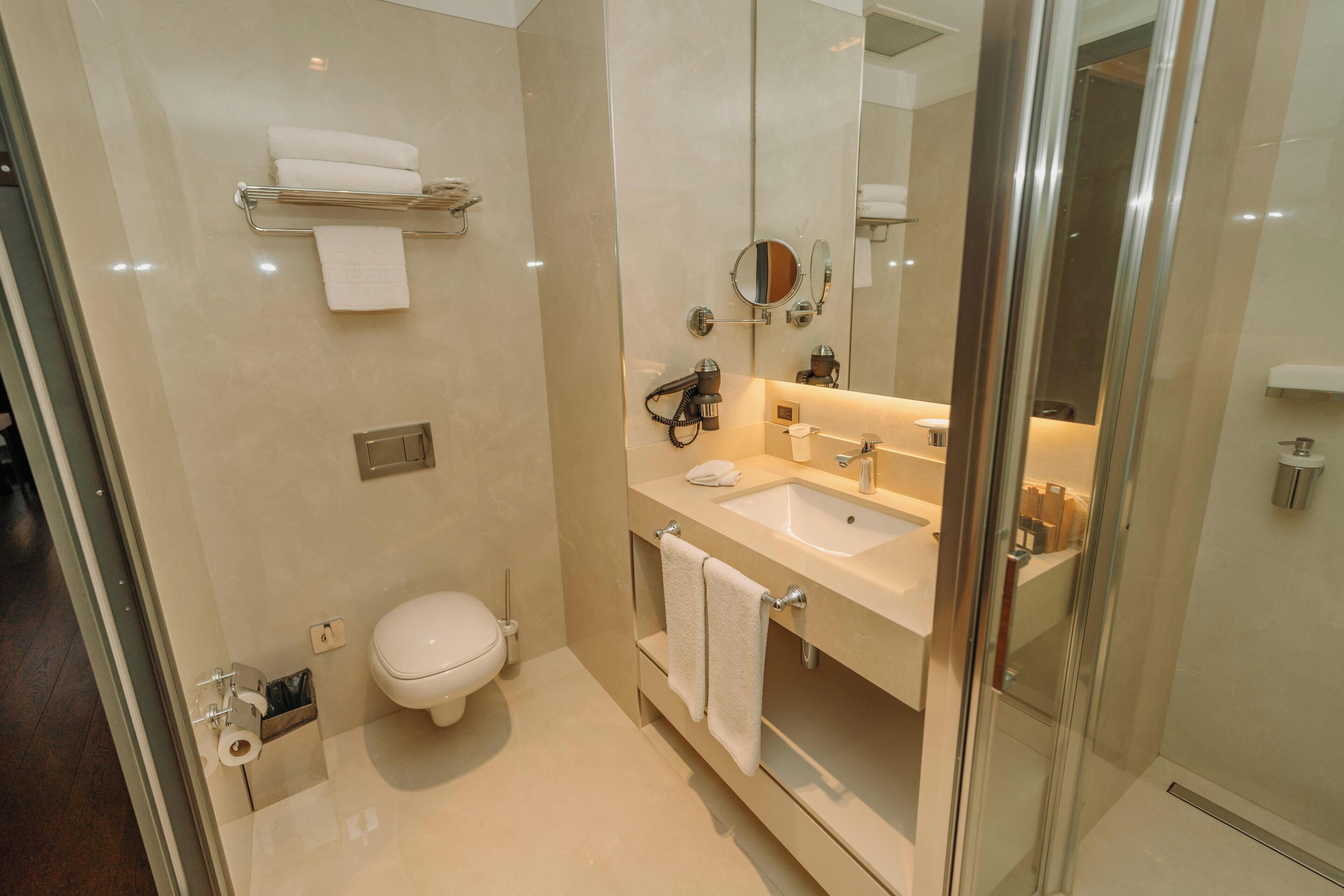 A modern bathroom with a glass shower enclosure, a toilet, a sink, and a vanity with a mirror.