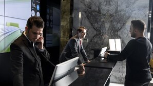 Un mostrador de recepción con una pantalla digital, una pared de mármol y una cámara de seguridad.