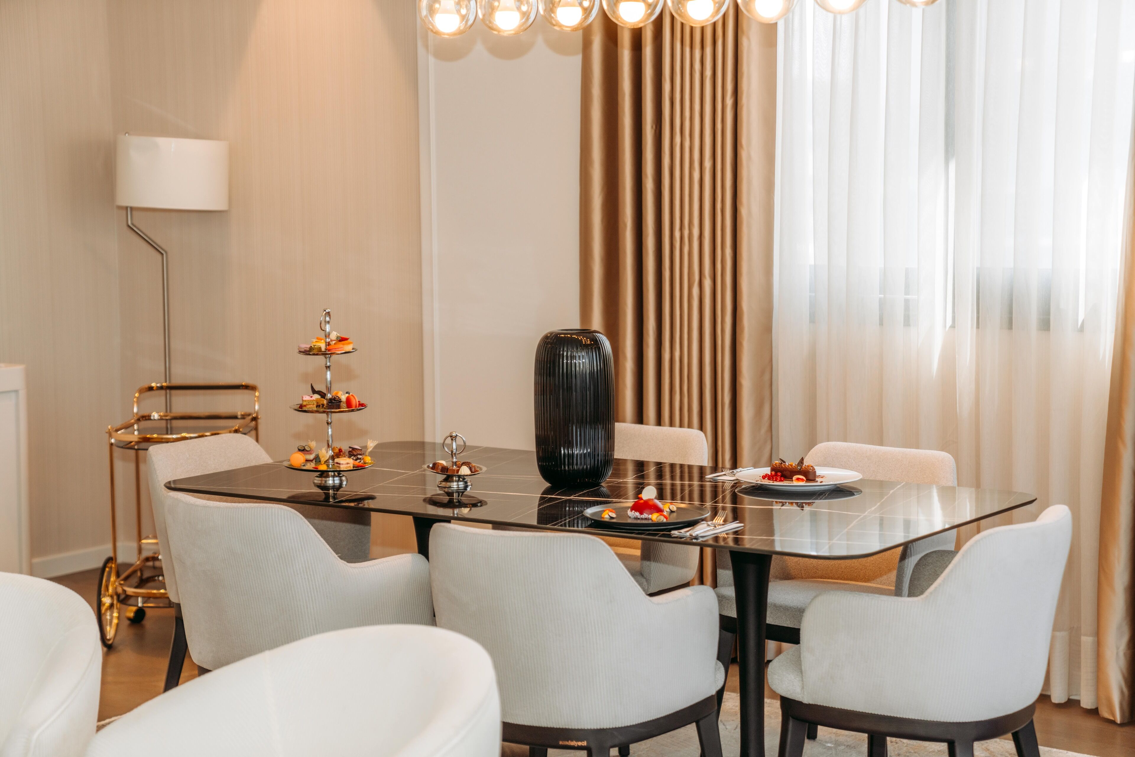 Un comedor moderno con una mesa de vidrio, sillas blancas y un florero decorativo.